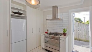 Una cocina compacta con horno integrado, estufa y refrigerador blanco.