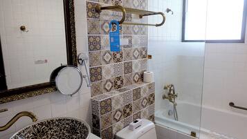 A bathroom with a large bowl sink, a toilet, a bathtub, and a shower.