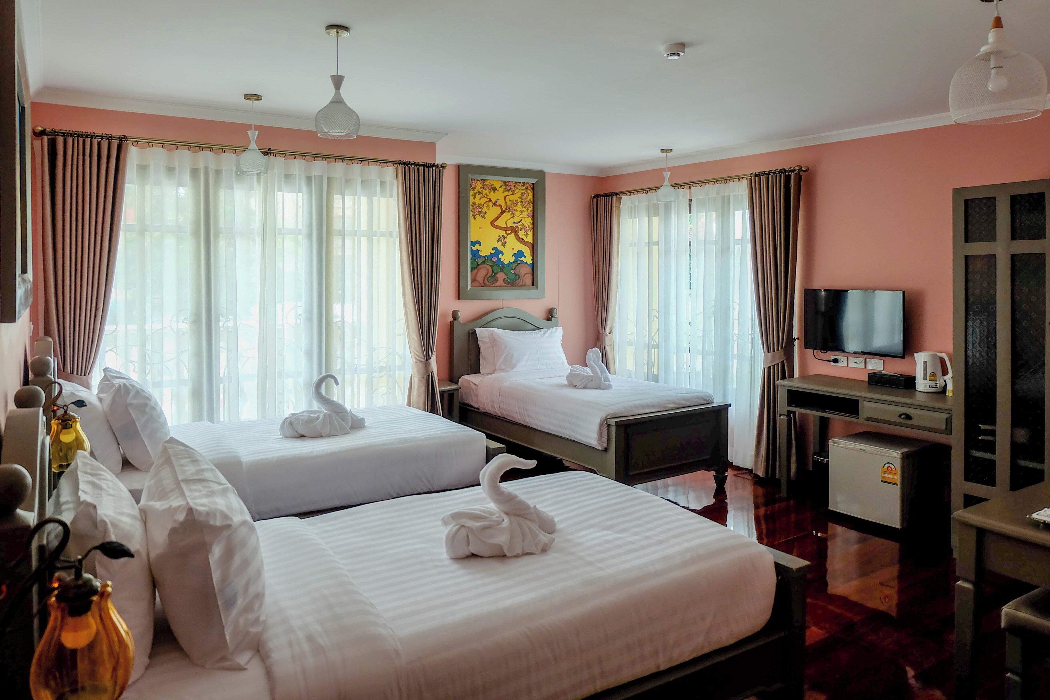 A hotel room with two beds, a desk with a television, and a small refrigerator.