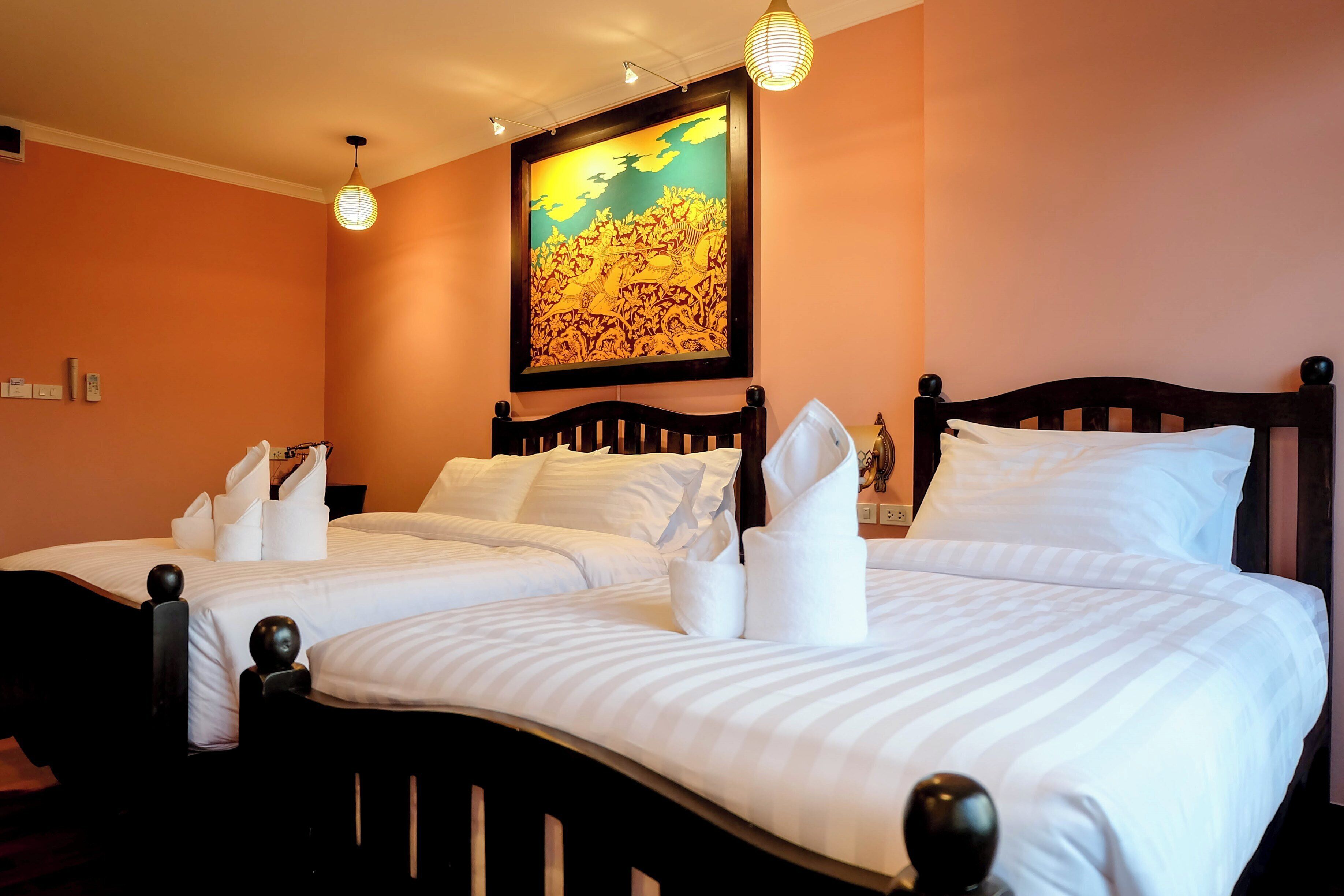 A hotel room with two beds, each with neatly folded towels and a wooden headboard.