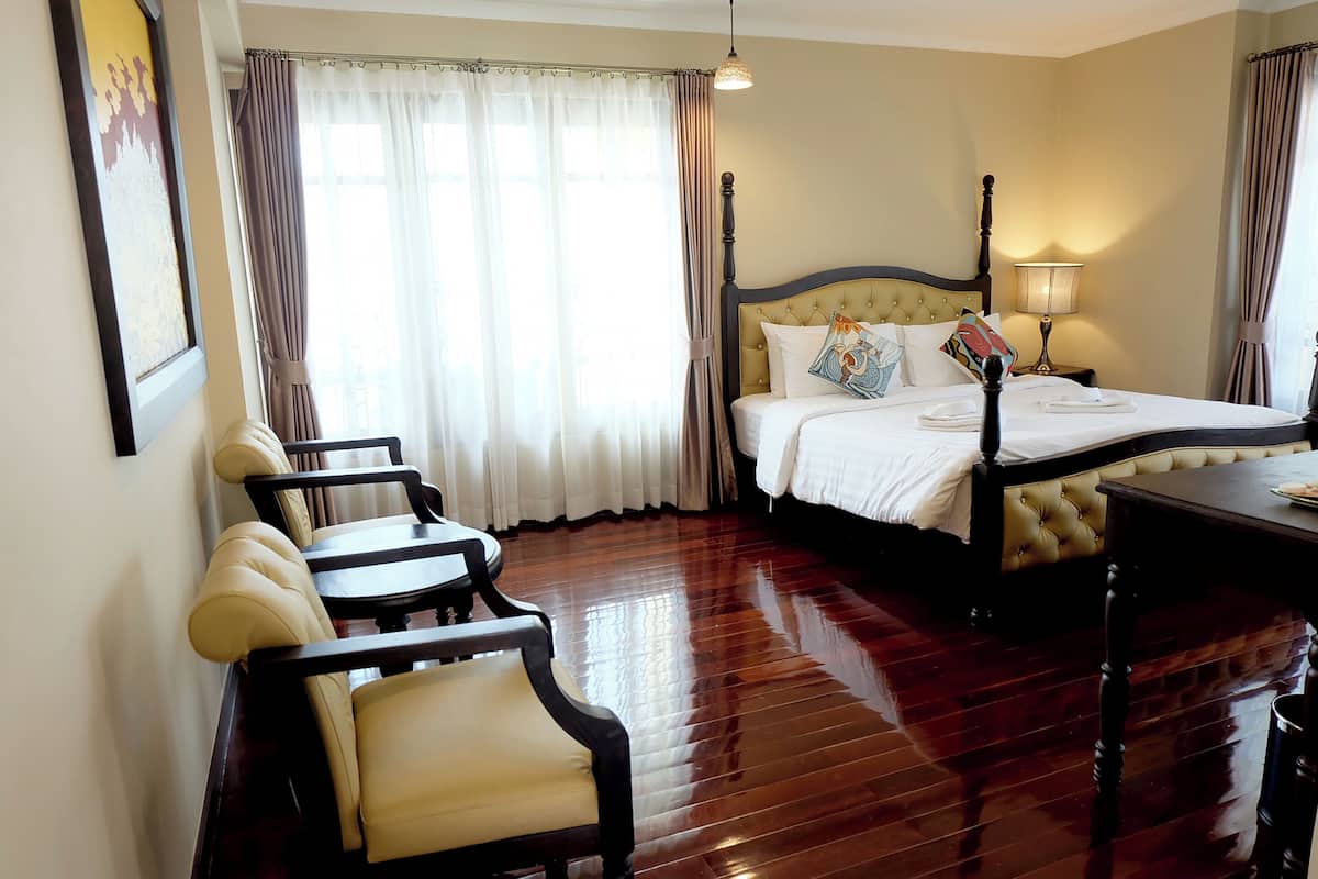 A hotel room with a bed, a desk, a chair, and a window with curtains.