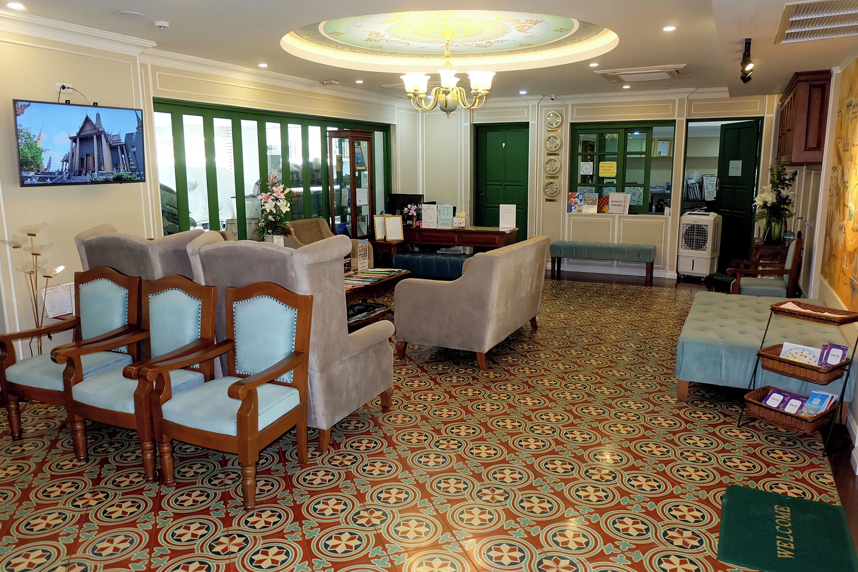 Eine Hotelhalle mit einem gemusterten Boden, Sitzgelegenheiten, einem Fernseher und einer Kristallleuchtre.