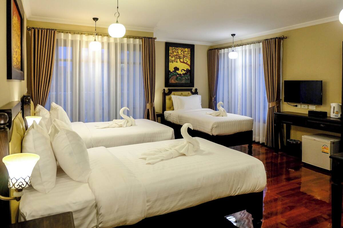 A hotel room with two beds, a TV, a desk, and a coffee machine.