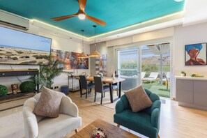 Una sala de estar moderna con comedor, ventilador de techo y un amplio ventanal con vistas al exterior.