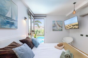 A modern hotel room with a bed, a TV, and artwork on the walls.