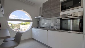 Uma cozinha moderna com uma janela redonda, eletrodomésticos embutidos e vista para o exterior.