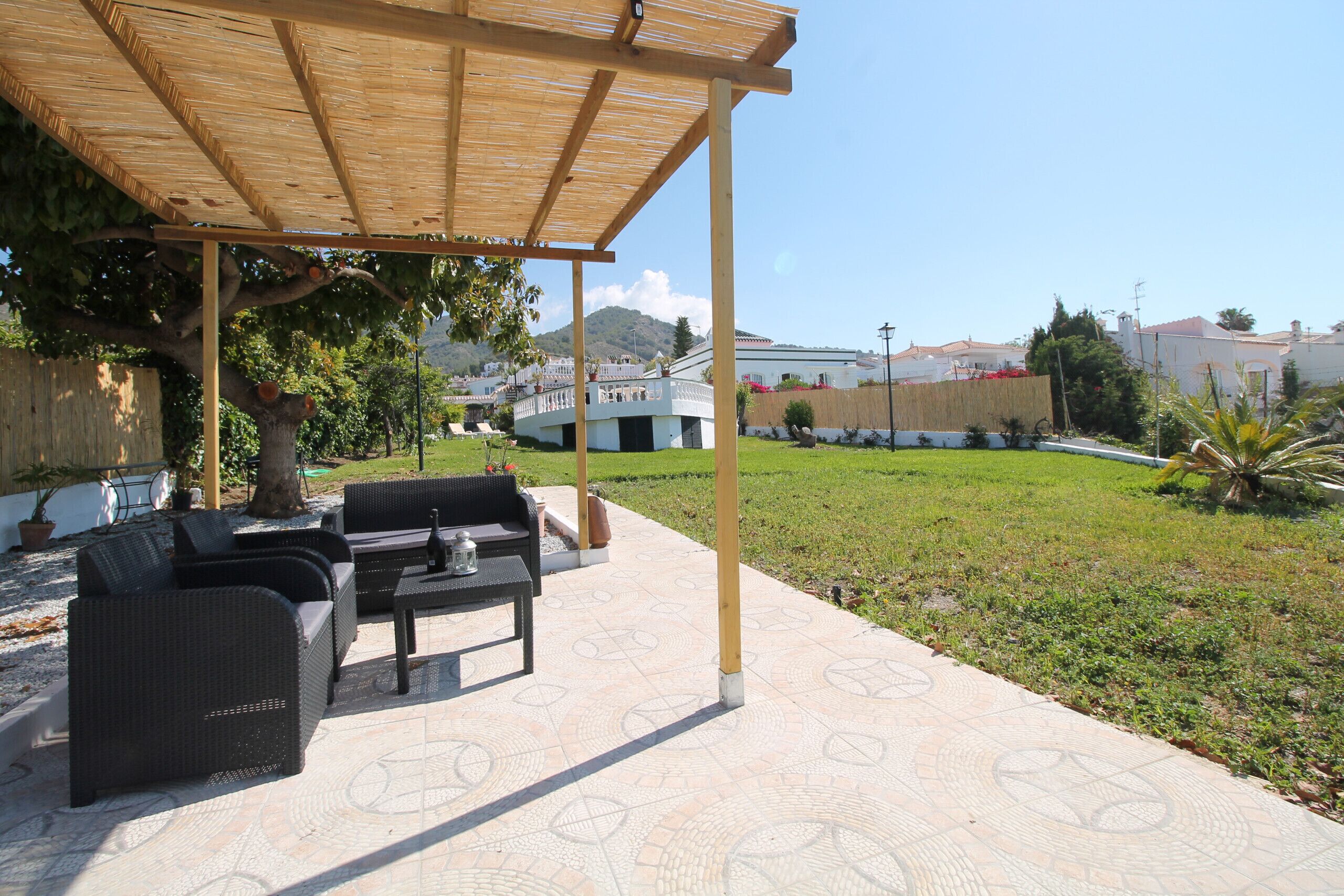 An outdoor patio with wicker furniture and a pergola.