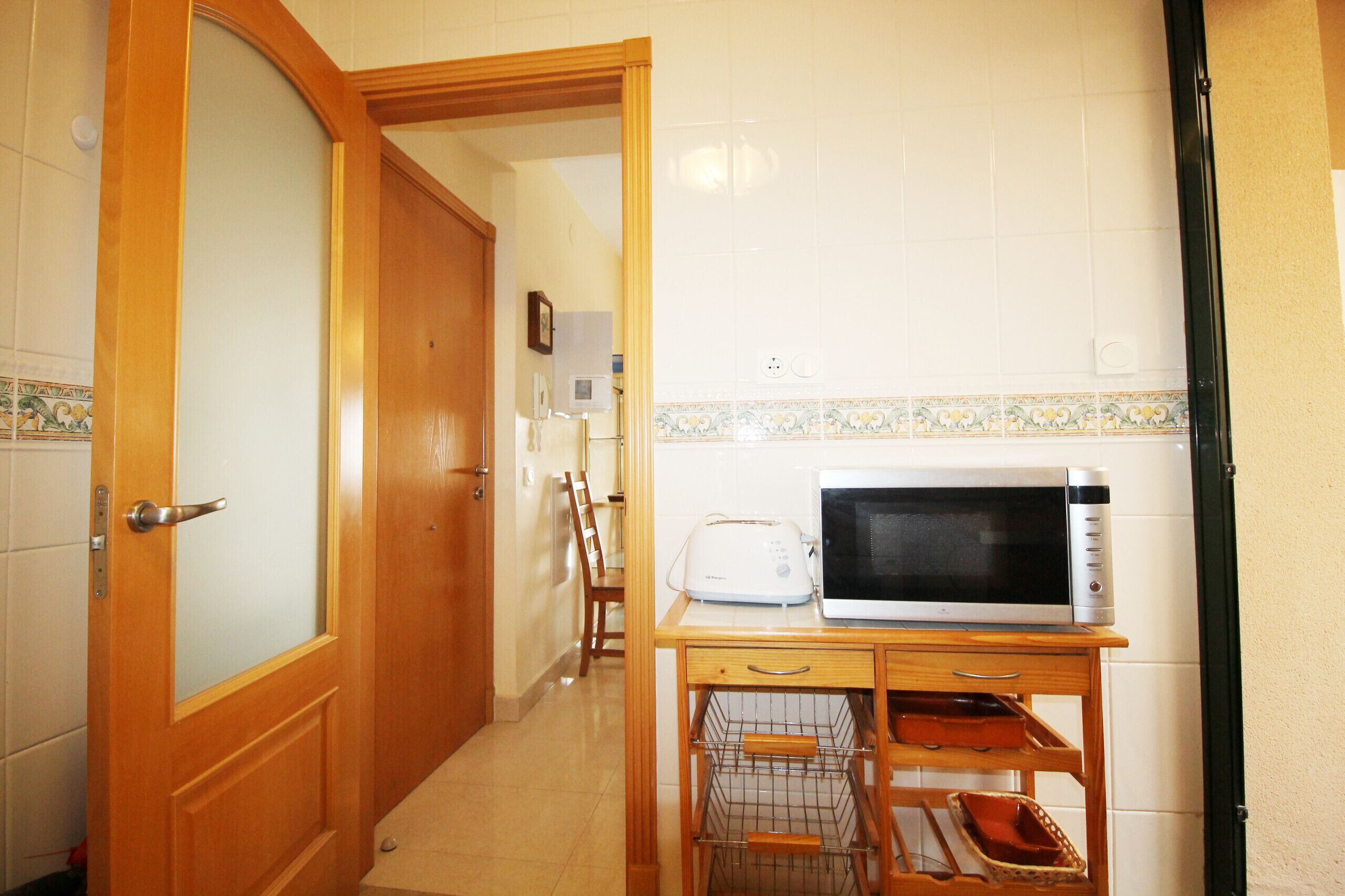 A kitchen with a microwave, toaster, and wooden cabinet.