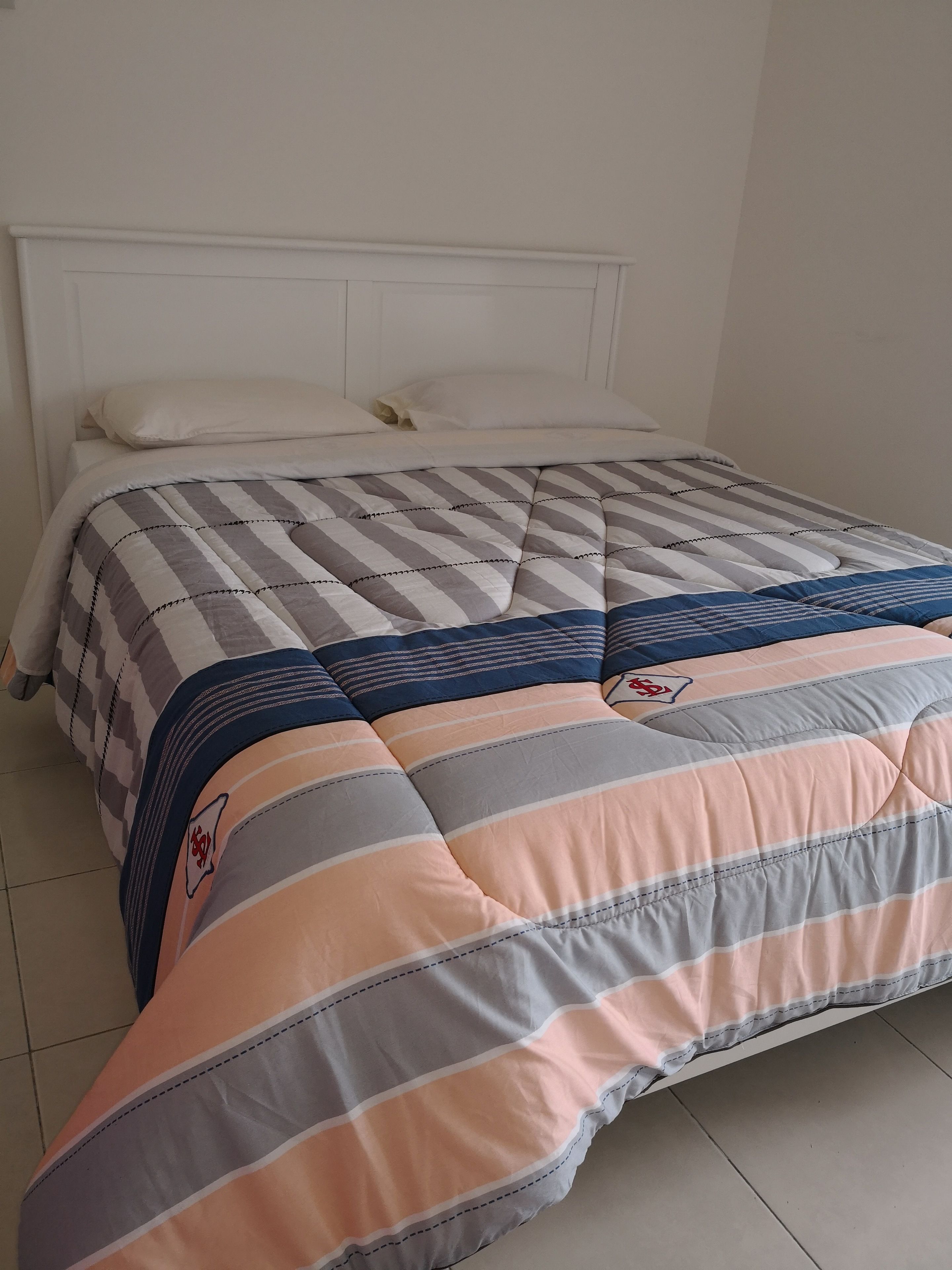 A neatly made bed with striped bedding and a quilted blanket.