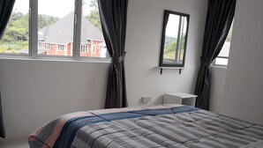 A bedroom with a bed, a window, and a view of buildings outside. - Goodlife Paradise Cameron Jaya (Tanah Rata)