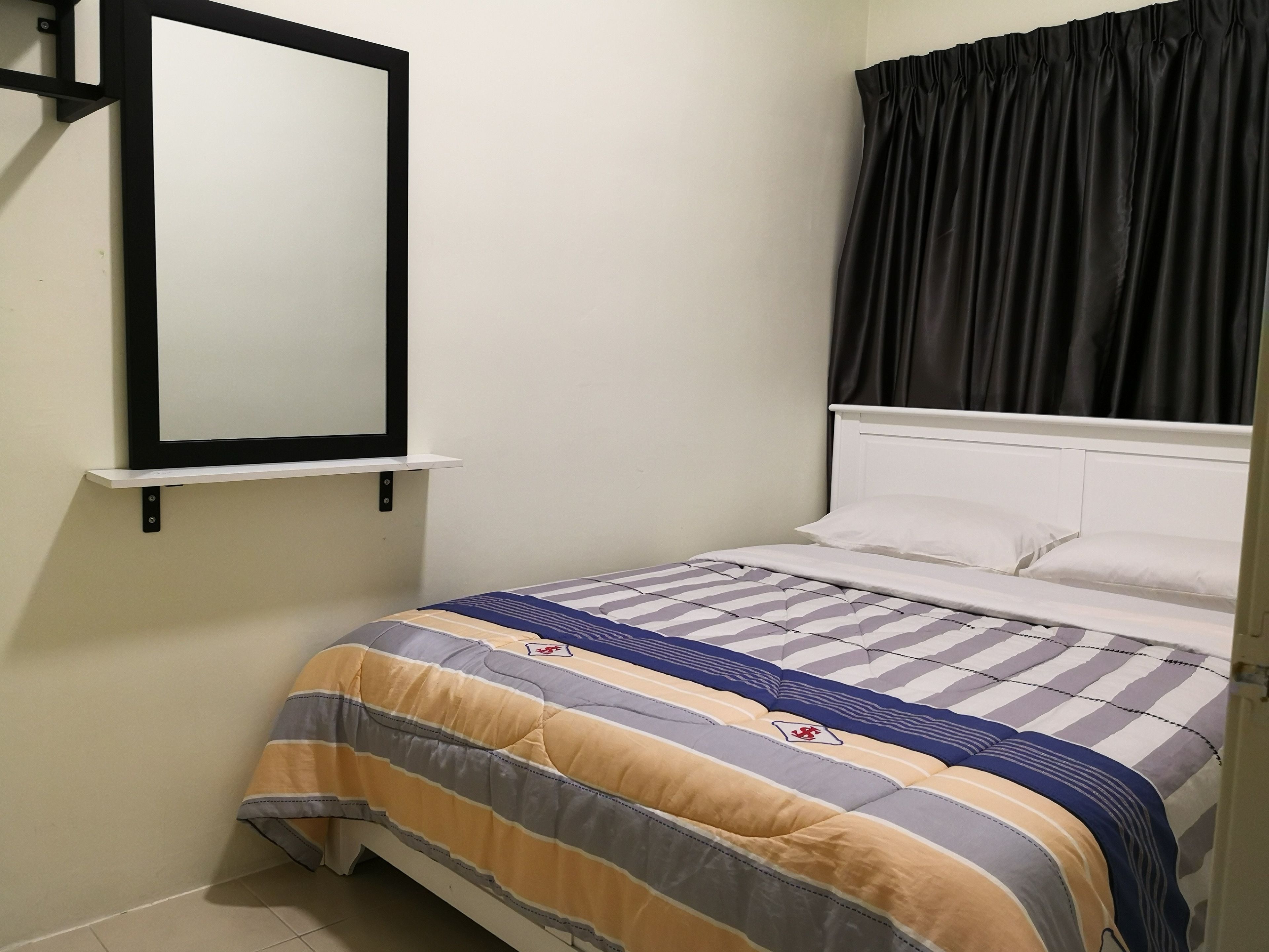 Un letto con copripiumino a righe, una testiera bianca e una tenda nera.