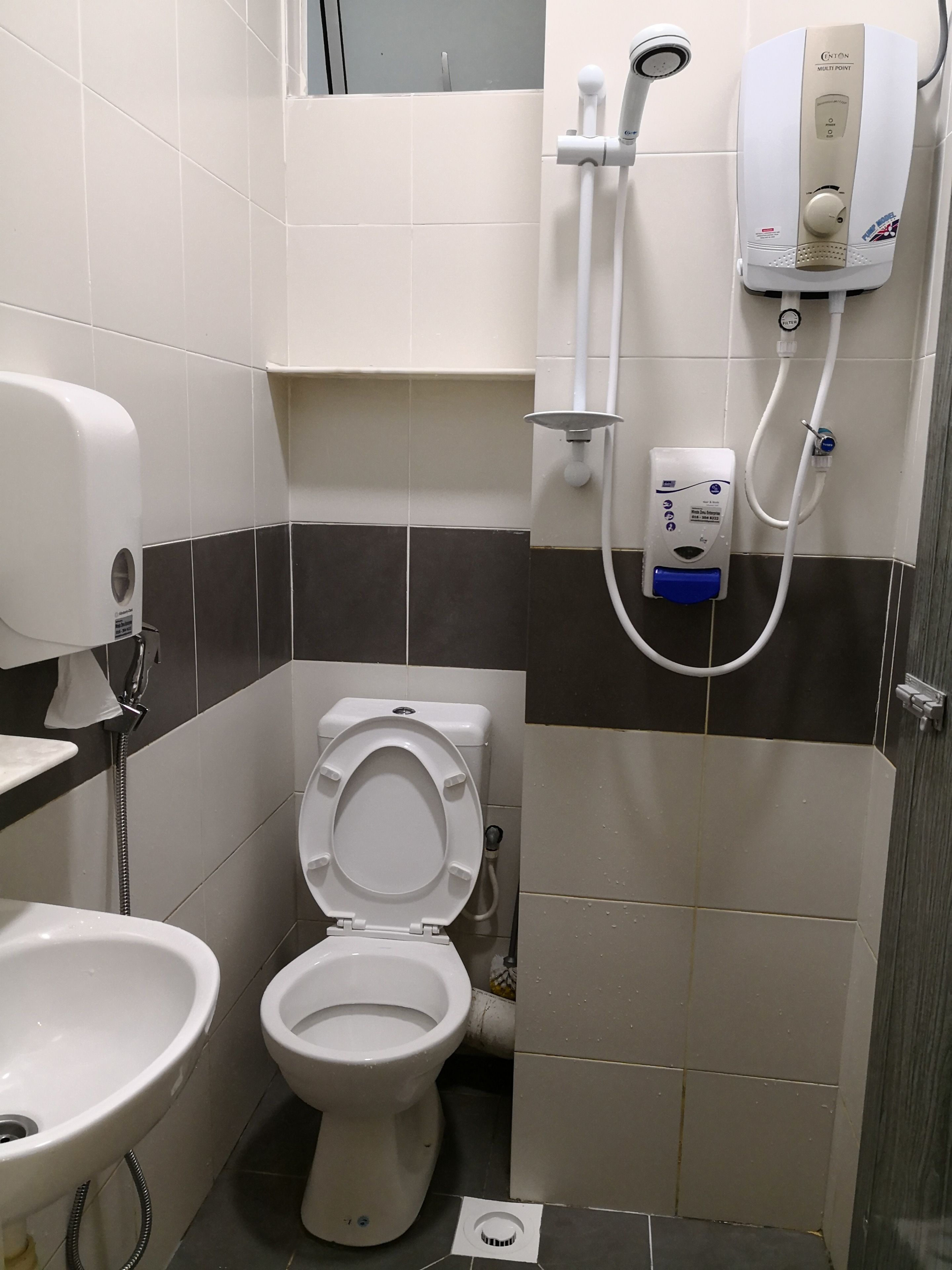 A bathroom with a toilet, sink, and a shower unit.
