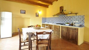 Una cocina con armarios de madera, salpicadero de azulejos y una mesa de comedor con sillas.