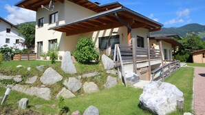 A modern two-story building with a wooden deck and a stone pathway leading to the entrance. - Nice apartment for 4 guests with WIFI, TV and patio (Helfenstein)
