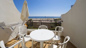 A balcony with a white table and chairs, a drying rack, and a beach view. - Amazing apartment on the seafront in Roses Inmosantos Oasis D4 (Rosas / Roses)