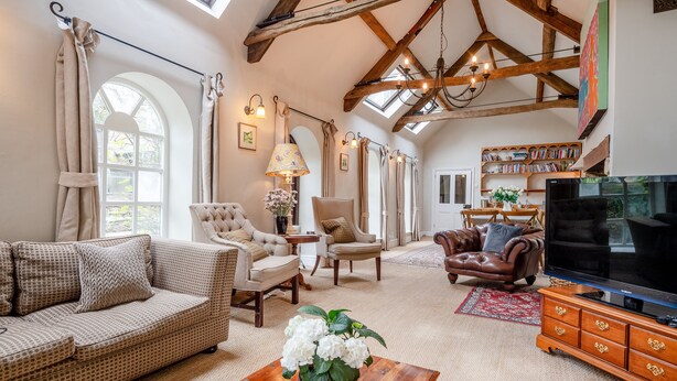 A spacious living room with high ceilings, a large TV, and a cozy fireplace.