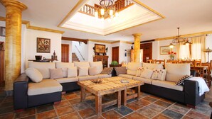 Un salón amplio con un sofá modular grande, una mesa de centro de madera y una araña.
