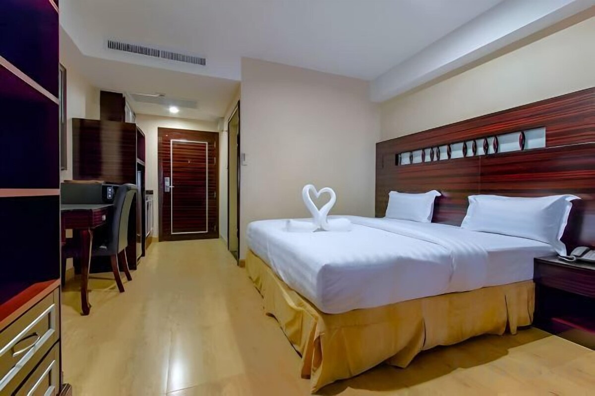 A hotel room with a bed, bedside table, and a desk with a chair.