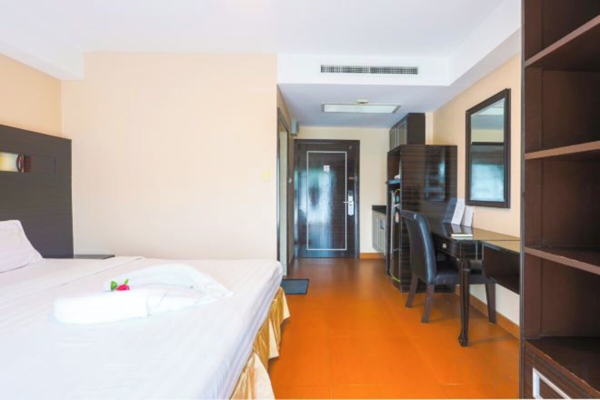 A hotel room with a bed, desk, and wardrobe.