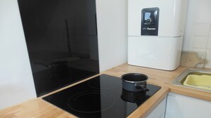 A kitchen with a black induction cooktop, a white refrigerator, and a wooden countertop. - Apartment/ flat - Concarneau (Concarneau)