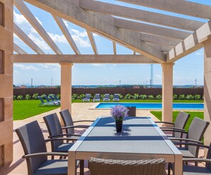 Un patio al aire libre con piscina, sillas de descanso y una mesa con sillas.