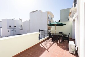 A balcony with a table and chairs, a green umbrella, and a white wall. - Rooms & Suites Terrace 3A, Arrecife, Lanzarote (Arrecife)
