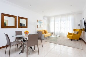 A modern living room with a dining area, a sofa, a yellow armchair, and a flat-screen TV. - Rooms & Suites Terrace 3A, Arrecife, Lanzarote (Arrecife)