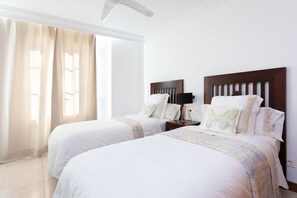 A hotel room with two beds, a ceiling fan, a nightstand with a lamp, and a window with curtains. - Rooms & Suites Terrace 3A, Arrecife, Lanzarote (Arrecife)