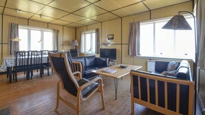 A cozy living room with a sofa, a dining table, and chairs. There is a TV and a lamp. - 4 bedroom beautiful home in Frøstrup (Frøstrup)
