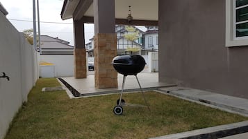 En trädgård med en grill, en vattenkran och en stenkiosk.