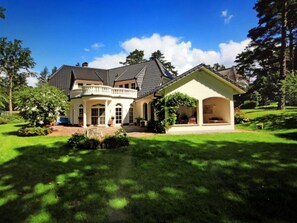 Une grande maison à deux étages, dotée d’un balcon et d’un porche abrité.