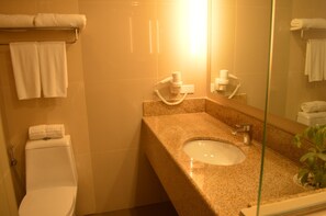 Un baño con inodoro, lavamanos y perchero para toallas.