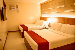 Habitación de hotel con dos camas, cabecera de madera, aire acondicionado instalado en la pared y mesita de noche con lámpara.