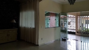 Um quarto espaçoso com uma grande janela, um lustre e vista para o exterior.
