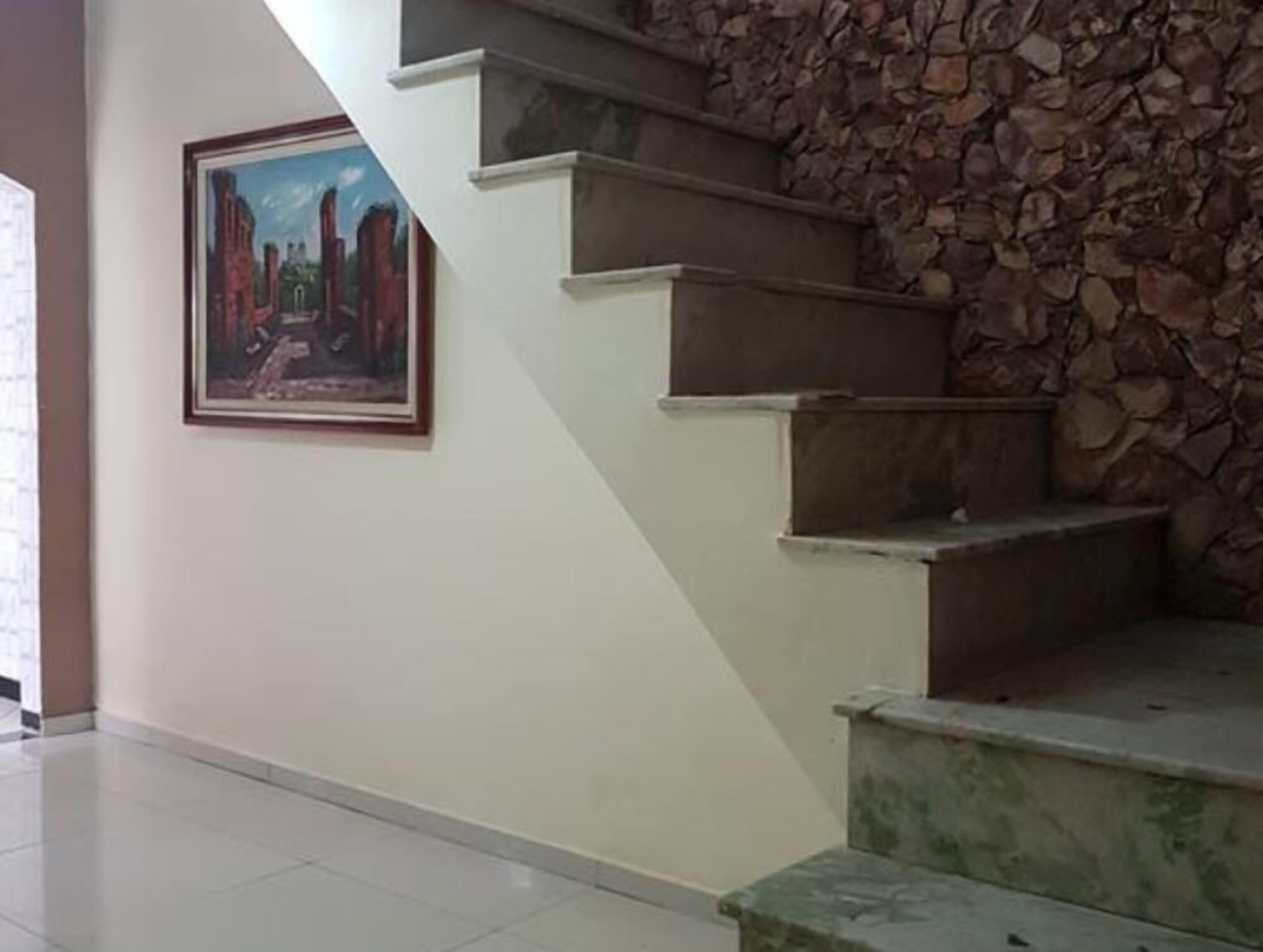 Eine Treppe mit einer Steinsäule und einem gerahmten Gemälde an der Wand.