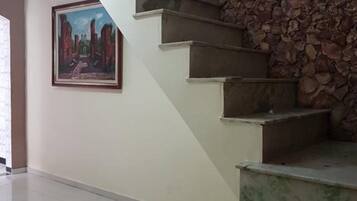 Eine Treppe mit einer Steinsäule und einem gerahmten Gemälde an der Wand.