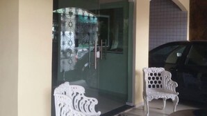 Entrada com porta de vidro e um banco do lado de fora.