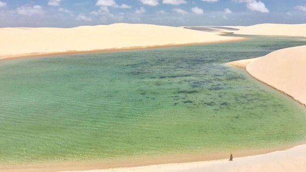 Paisagem desértica com dunas de areia e um corpo d'água.