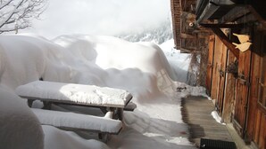 Un edificio de madera con un banco cubierto de nieve y un paseo de madera.