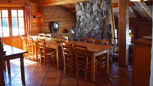 Un interior rústico de madera con una pared de piedra, una mesa de comedor de madera y sillas.