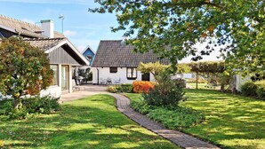 Et traditionelt hus med en anlagt havegang, der fører til en trædør.