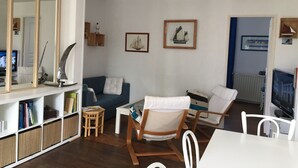 A living room with a sofa, chairs, a coffee table, a TV, and a bookshelf.