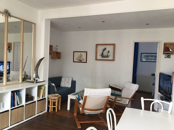 Un saló amb un sofà, cadires, una taula de centre, un televisor i una estanteria.