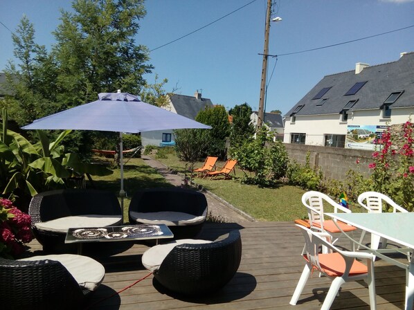 Une terrasse extérieure avec des meubles en osier, une table et un parasol.