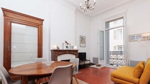 A dining area with a wooden table and chairs, a fireplace, and a television. - Bessons-1884-Bourgeois style apartment with large terrace (Cannes)