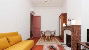 A living room with a yellow sofa, a dining table with chairs, a fireplace, and a TV. - Bessons-1884-Bourgeois style apartment with large terrace (Cannes)