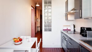 A compact kitchen with a dining area, featuring a white table with a fruit bowl, a toaster, and a coffee maker. - Bessons-1884-Bourgeois style apartment with large terrace (Cannes)
