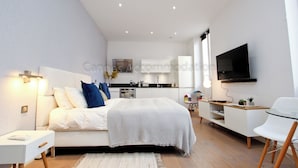 A modern bedroom with a bed, bedside table, and a TV mounted on the wall. - Pampelonne-2209-A luxurious studio in the center (Cannes)