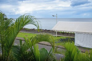 A coastal view with a white tent-like structure, a street lamp, and a clear sky.