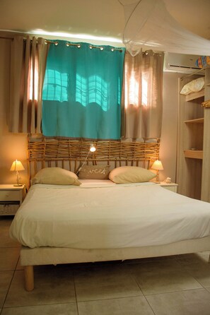 A bed with two pillows, a bedside lamp, and a headboard with a window view.
